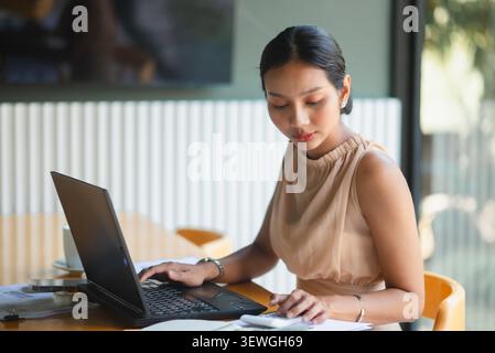 Businesswoman using laptop and calculator with financial reports on office desk, analyzing numbers for accounting, budget planning, online work, produ Stock Photo