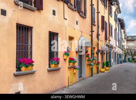 Via Giuseppe Piana, a narrow cobblestone street in the historic center of Sirmione, Lombardy, Northern Italy, featuring traditional colorful buildings Stock Photo