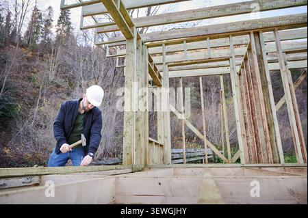 Contractor securing timber structure outdoors, concept of manual effort, building industry, site activity and residential construction Stock Photo