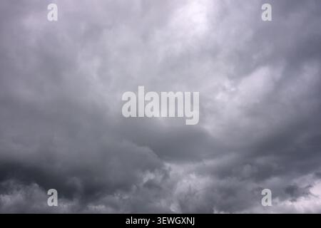 Stormy gray clouds fill the sky, heavy and dark. No animals or plants visible. Atmosphere suggests impending rain or thunderstorm. Moody, dramatic sky Stock Photo