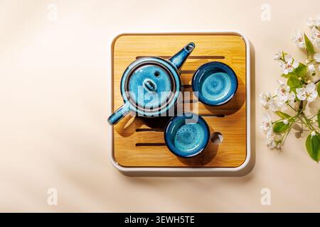 Blue ceramic teapot with blooming spring branch on wooden tray in minimal asian style composition Stock Photo