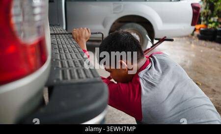 Mechanic changing car tire using jack, working on vehicle repair and service Stock Photo