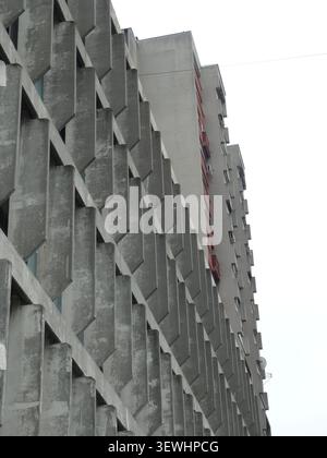 Concrete building facade showing brutalist architecture and repetitive geometric patterns looking up Stock Photo