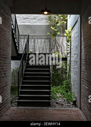 Modern Industrial Black Metal Staircase with Climbing Green Plants and Brick Walls Stock Photo