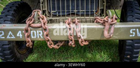 Heavy rusted towing chains wrapped around the bumper of a vintage military jeep. Stock Photo