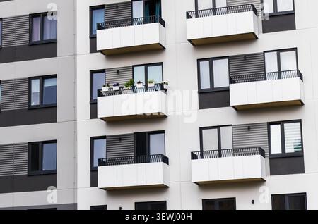 Architectural pattern of modern apartment building facade with minimalist white geometric balconies and textured panels. Stock Photo