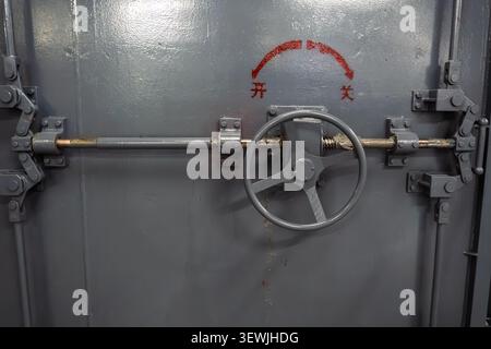 Heavy duty steel door with secure turn wheel mechanism in industrial setting. Stock Photo