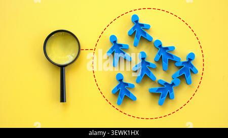 Target audience research and market segmentation concept with a magnifying glass focused on a group of blue figures Stock Photo