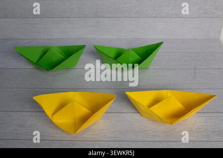 Line up of two color groups of origami paper boat on a wooden chair background Stock Photo