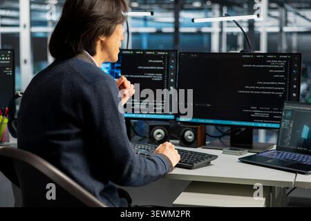 Computer scientist uses a desktop computer in a data center to support supercomputer management and reliable server workflows. Stock Photo
