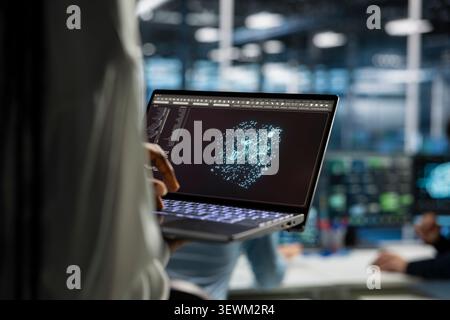 Engineer works with a laptop in a server hub to support artificial intelligence systems. Stock Photo