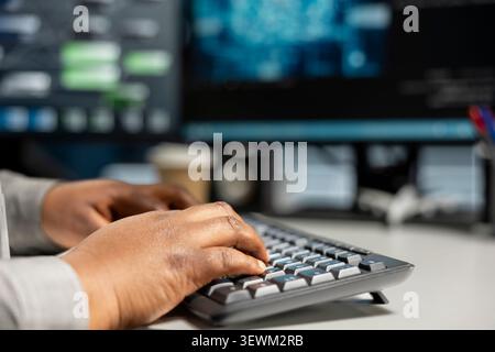 Data center programmer uses a desktop computer in a data center to manage AI systems and optimize server infrastructure. Stock Photo