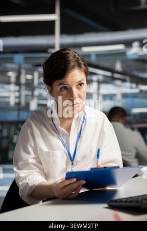 System administrator uses a clipboard in a data center to monitor equipment, manage workflows, and support reliable infrastructure. Stock Photo