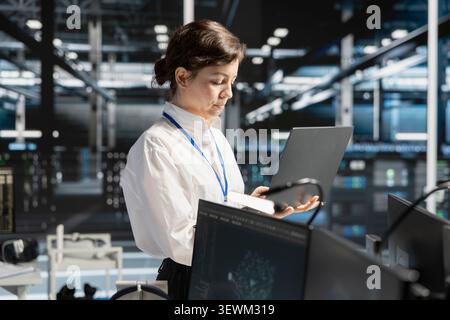 IT specialist reviews performance analytics on a laptop computer in a data center to optimize storage systems and resource use. Stock Photo