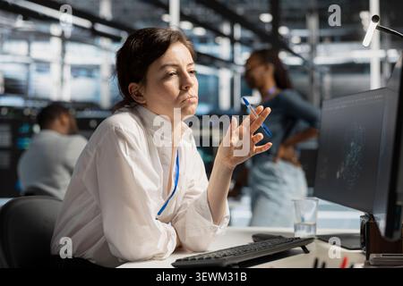 Data center engineer uses a desktop computer in a data center to support failure detection and reliable server workflows. Stock Photo