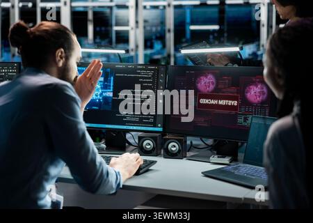 Pensive data center technicians review system data in a data center while planning repairs for performance and hardware issues. Stock Photo
