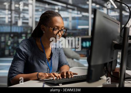 System operator uses a desktop computer in a data center to monitor equipment, manage workflows, and support reliable infrastructure. Stock Photo