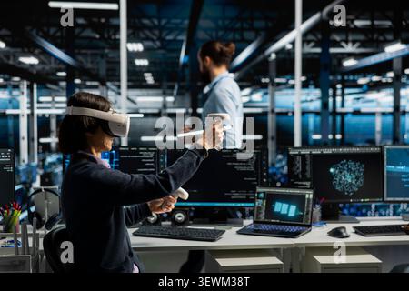 Data center technician uses a VR headset to inspect AI neural networks and server systems in a high-tech facility. Stock Photo