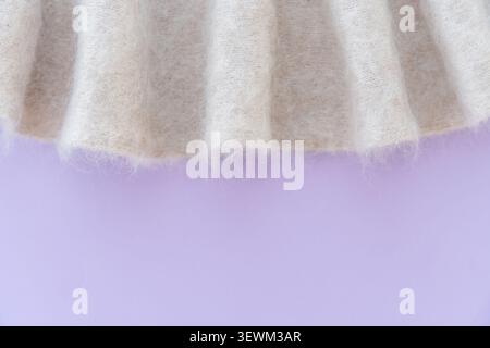 Soft white mohair wool fabric with purple background and pleats. Stock Photo