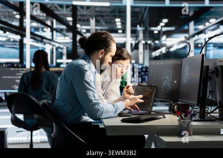 Data center colleagues collaborate on coding and AI automation scripts while reviewing server infrastructure together. Stock Photo
