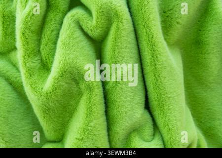 Close-up of vibrant green faux fur fabric, showcasing soft texture and elegant folds Stock Photo