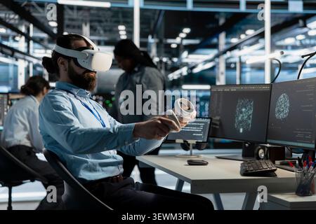 Software developer uses a VR headset to inspect AI neural networks and server systems in a high-tech facility. Stock Photo
