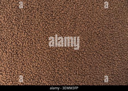 Macro shot of brown fashion teddy sherpa fleece recycled fabric showcasing its soft curly texture. Stock Photo