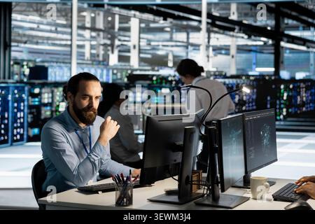 Data center technician uses a computer to run diagnostics, update servers and check infrastructure performance. Stock Photo