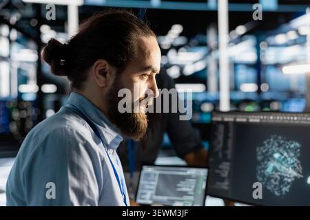 Data center technician uses a computer to run diagnostics, update servers and check infrastructure performance. Stock Photo