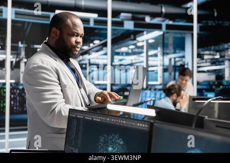 System administrator uses a laptop to run diagnostics, update servers and check infrastructure performance. Stock Photo
