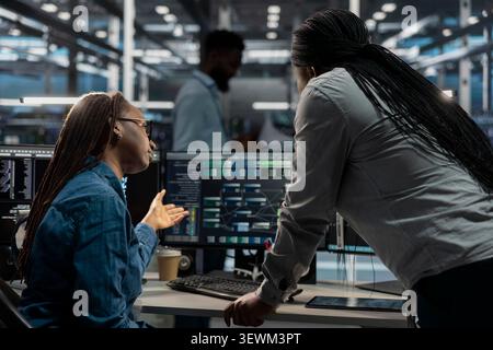 Data center colleagues collaborate on coding and AI automation scripts while reviewing server infrastructure together. Stock Photo