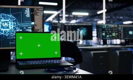 IT specialist reviews neural network visualization on green screen computers in a server room during software debugging work. Stock Photo