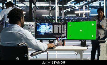 Worker using a wheelchair operates AI node tree software in a data center to monitor performance data. Stock Photo