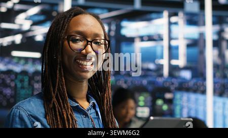 Data center engineer monitors data center metrics on a digital device to improve equipment performance. Stock Photo