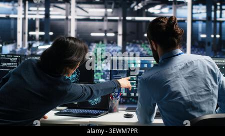 System administrator uses deep learning tools on a digital device in a server room to improve AI operations and system efficiency. Stock Photo