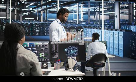 Technician uses a computer workstation in a server farm to categorize unstructured data with node tree systems. Stock Photo