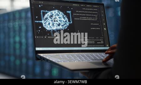 Computer scientist uses laptop-based deep learning tools in a server room to improve AI operations and system efficiency. Stock Photo