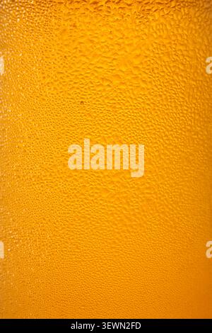water condensation drops on cold orange liquid container surface in full frame, wet yellow liquid with fresh dew macro texture, refreshing summer Stock Photo