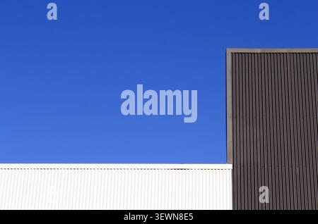 Minimalist architectural detail featuring clean lines of a building exterior against a stark, solid blue sky Stock Photo