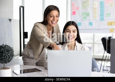 Two professional women using laptop working together in modern office Stock Photo