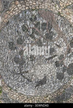 Close view of a crane and pine pebble mosaic pavement at Master of Nets Garden in Suzhou, China, with textured stones and brick outlines Stock Photo