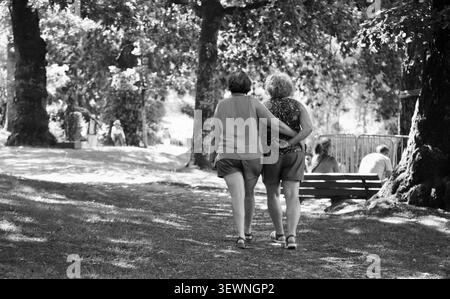 Two ladies embracing at the lakeside, in Bagnoles de l'Orne, in North West France, during the heatwave in 2026 Stock Photo