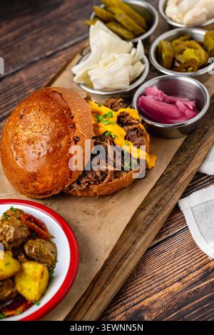 Slow cooked pulled rib beef burger with melted cheese and sides Stock Photo