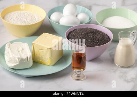Baking ingredients with a piece of butter, eggs, quark and poppy seeds in colorful bowls Stock Photo