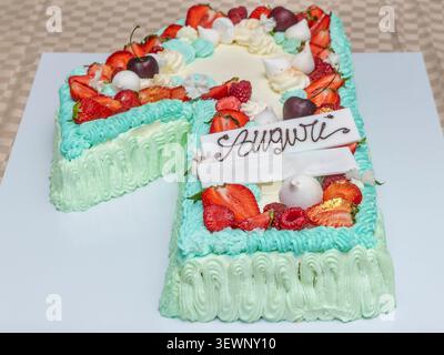 A birthday cake with fruit and meringues in the shape of the number 1 and the word "Auguri" (happy birthday in Italian) Stock Photo