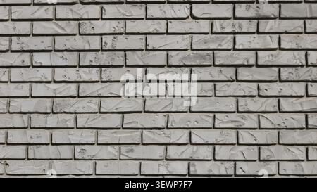 gray wall made of decorative brick. The texture is textured with dents and scratches to give it an antique look. The masonry is smooth, with fine join Stock Photo