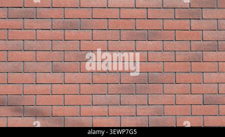 red brick wall with smooth horizontal masonry. The surface of the blocks is rough and grainy. The shades range from terracotta to dark brown Stock Photo