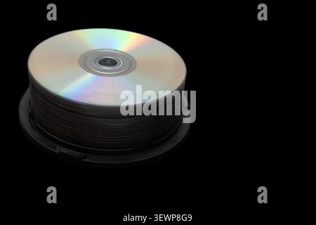 The image shows a stack of compact discs in a black case. The discs have shiny surfaces that reflect light. The background is solid black. Stock Photo