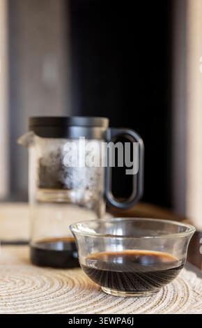 Glass teapot for brewing Chinese tea with a glass tea bowl on the kitchen table. Stock Photo
