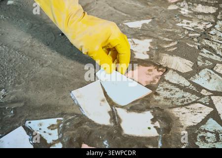 Hand placing broken ceramic tiles into wet mortar, creating mosaic. Upcycling old materials Stock Photo